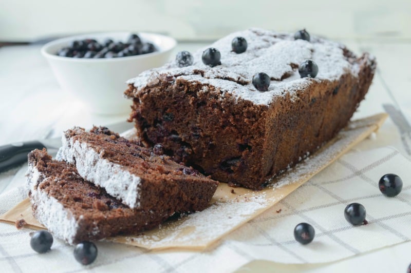 a cake sliced sitting on parchment paper with blueberries
