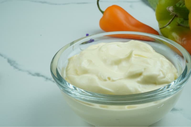 a bowl of homemade mayonnaise in front of vegetables