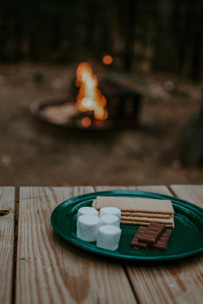 a plate of s'mores near a camping fire