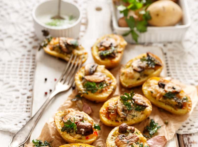 potatoes stuffed with cheese on a white dish with herbs