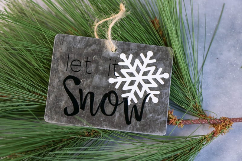 a Christmas gift tag with a snowflake on a pine bough