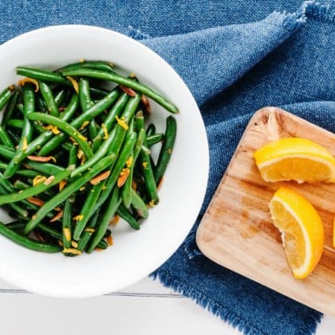 green beans in a white bowl with oranges and almonds