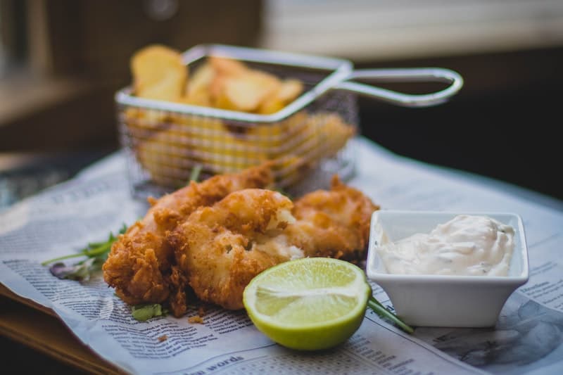 a fish dinner with chips and a lime