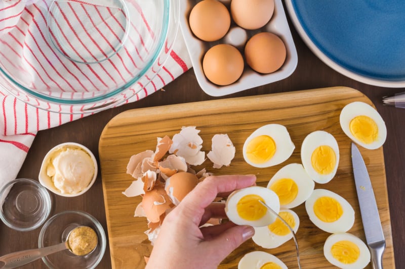 sliced eggs on a cutting board near ingredients in bowls