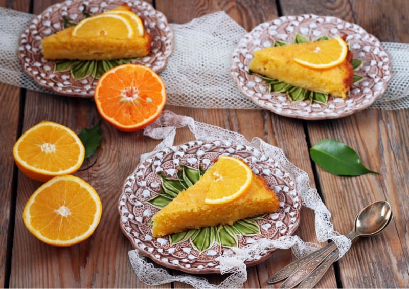 a slice of cake on brown plates with orange halves