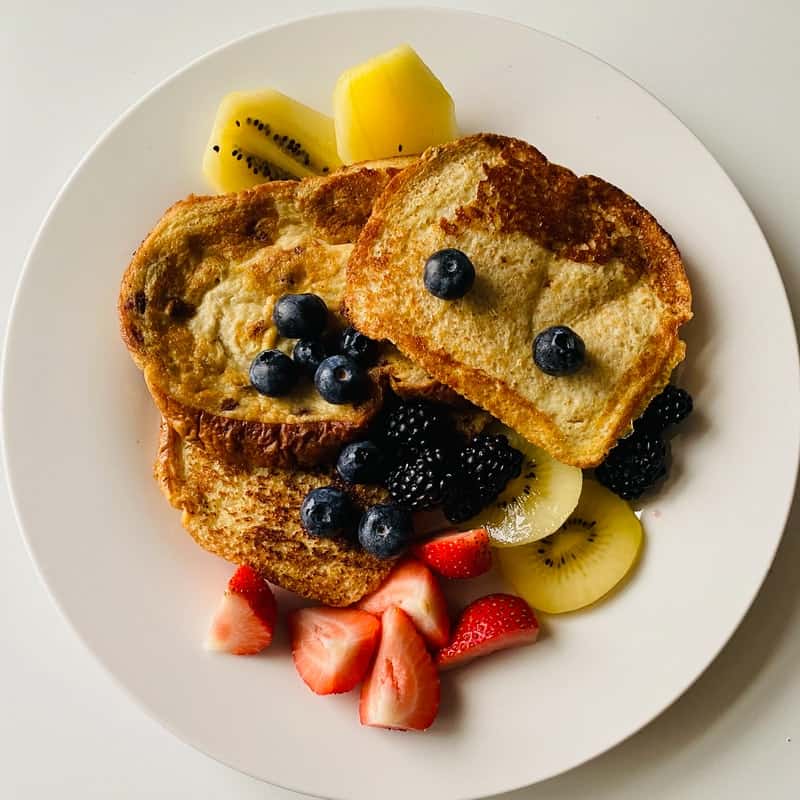 French toast with fruit on a white plate