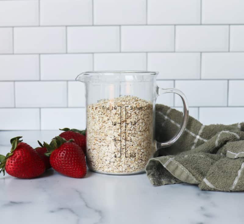 oats in a measuring cup near strawberries
