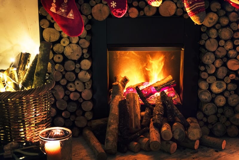 a fireplace with a fire going and Christmas stockings hung