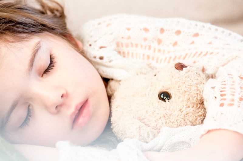 child sleeping with a teddy bear