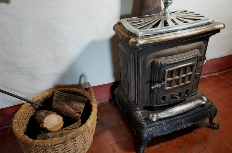 a wood stove with wood in a basket