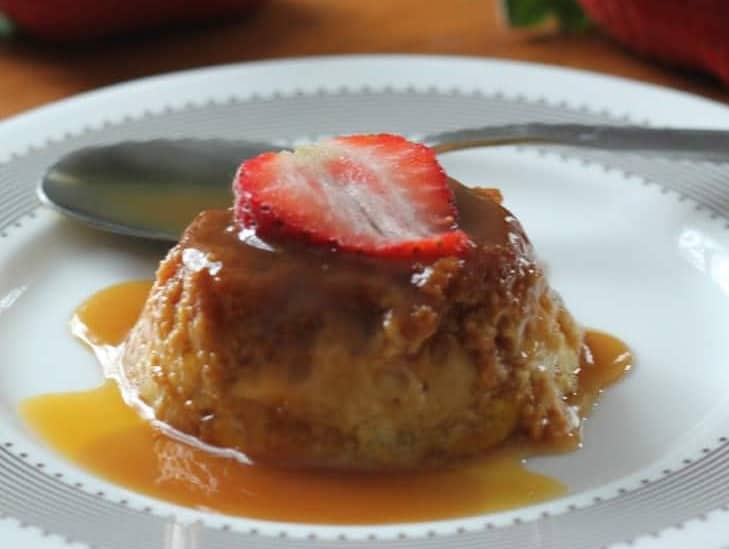 crockpot flan on a white dish with a strawberry and caramel sauce
