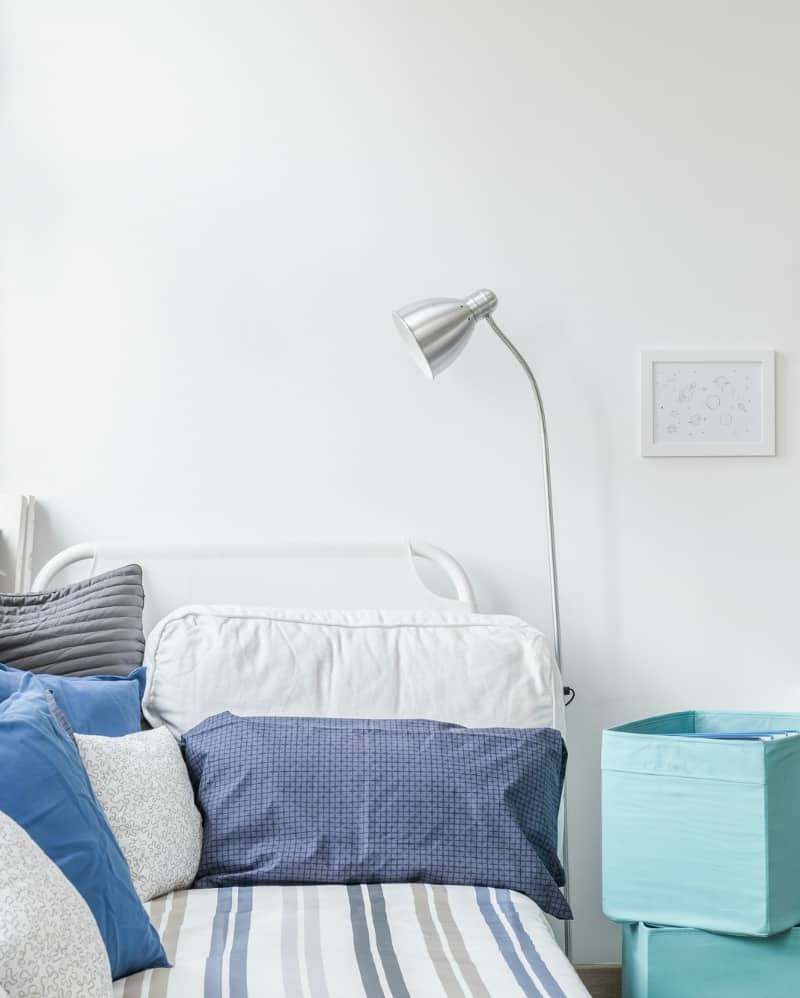 a bed with blue pillows and storage cubes against a white wall