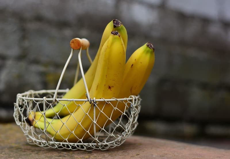 a wire basket holding three yellow bananas