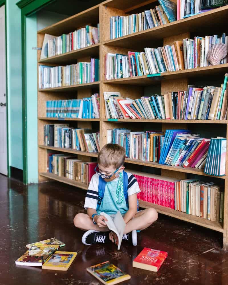 a child sitting on the ground reading in the library