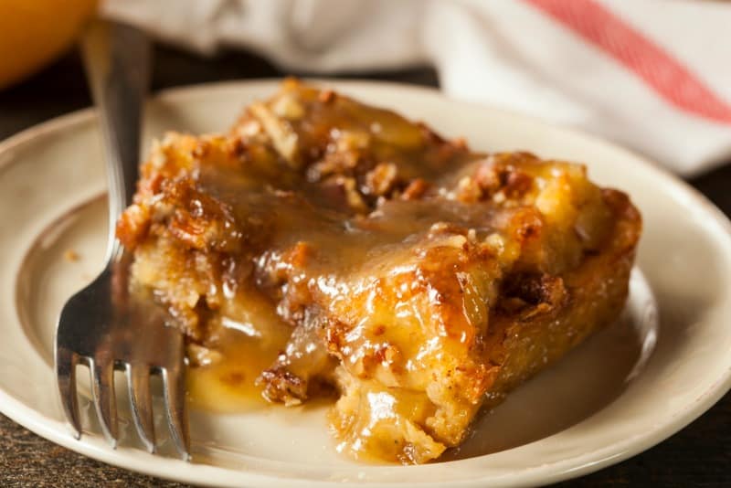 a slice of bread pudding on a plate with praline topping