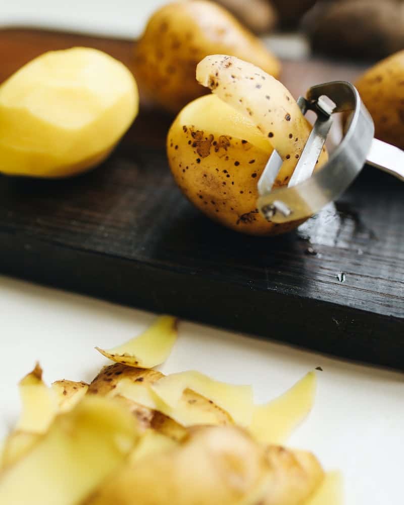 peeling potatoes on a cutting board