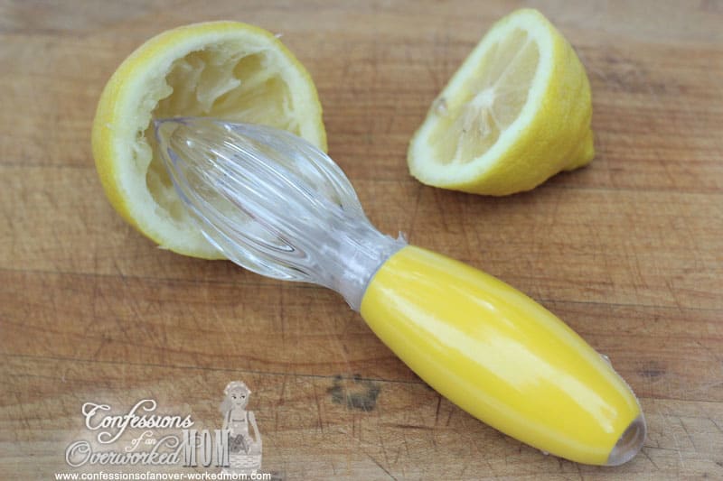 a lemon and a citrus reamer on a cutting board