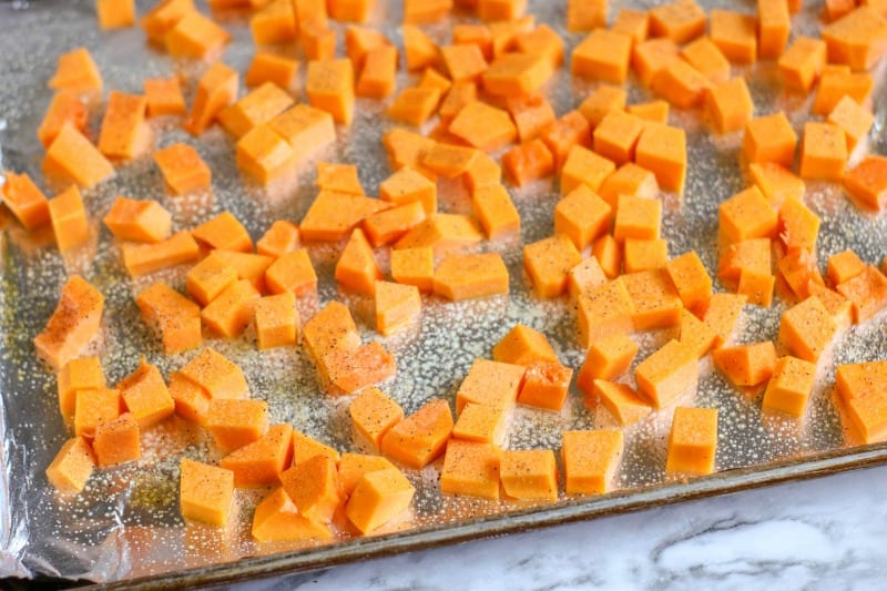 cubes of squash on a cooking sheet lined with foil