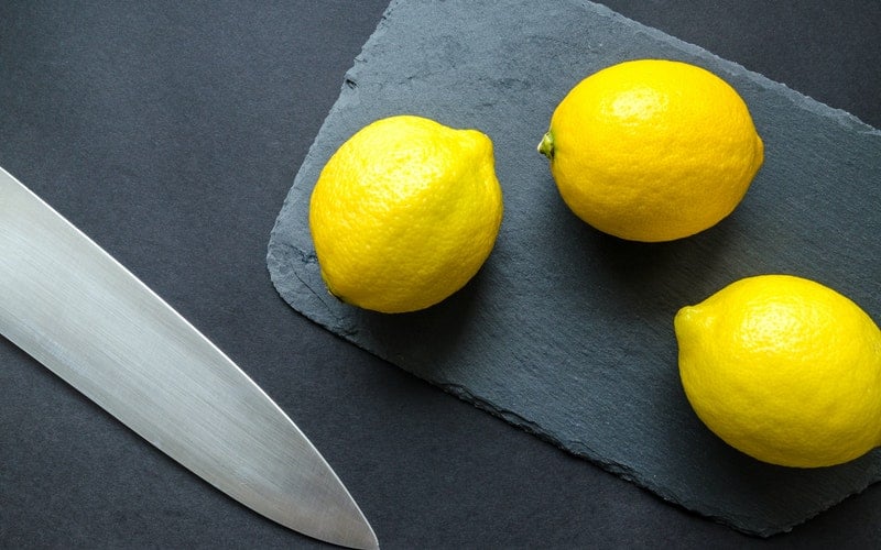 lemons on a slate cutting board near a knife