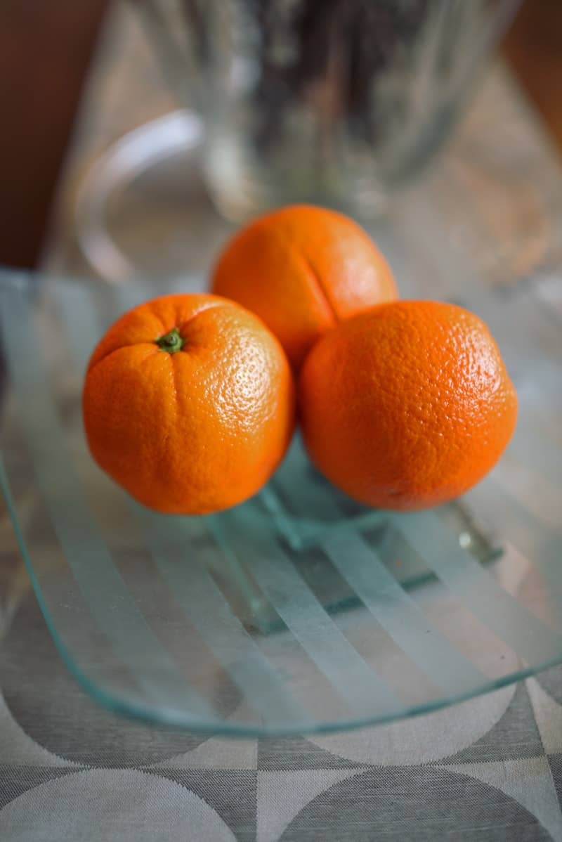 three oranges on a glass plate