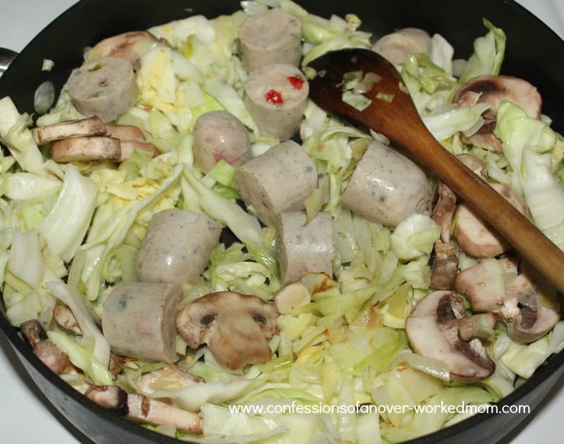 cooking cabbage, sausage and mushrooms in a pan