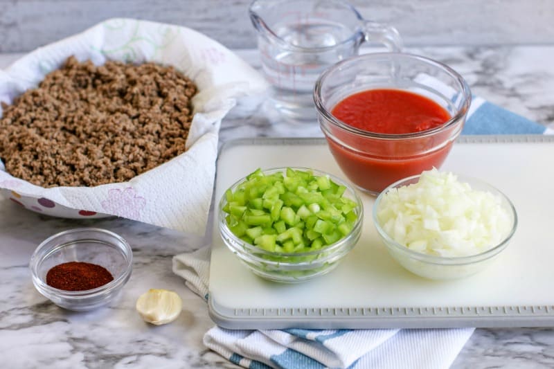 ground beef, tomato sauce, onions, celery and spices in clear bowls