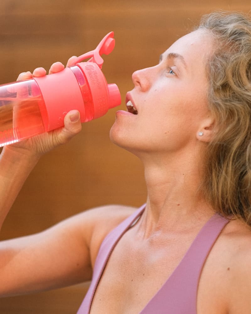 a woman drinking from a sport bottle