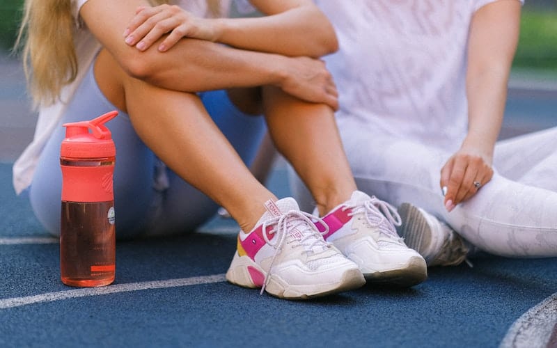 two women sitting with a sports drink after tennis