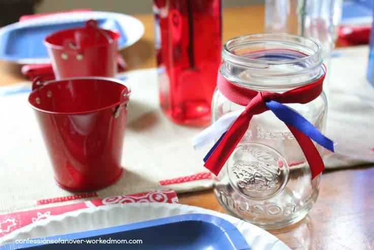 Mason jar glasses with red and blue ribbon on a table