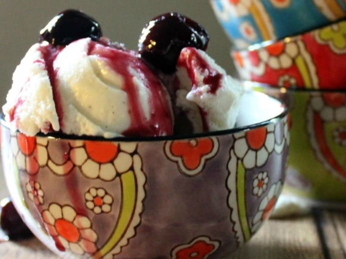 close up of a bowl of vanilla ice cream with cherry sauce on it