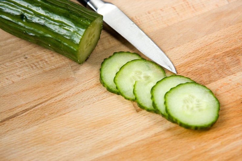 sliced cucumbers on a cutting board with a knife