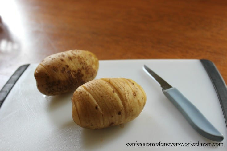 two potatoes on a white cutting board with a knife