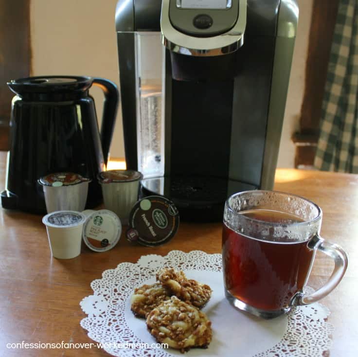 a coffee maker with a cup of coffee and three cookies