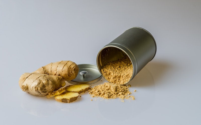a ginger root next to a tin of ginger powder
