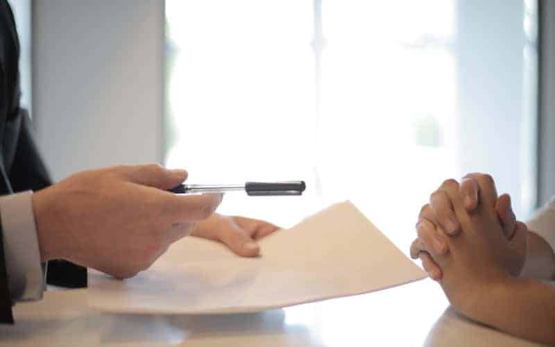 two people holding a pen and document to sign