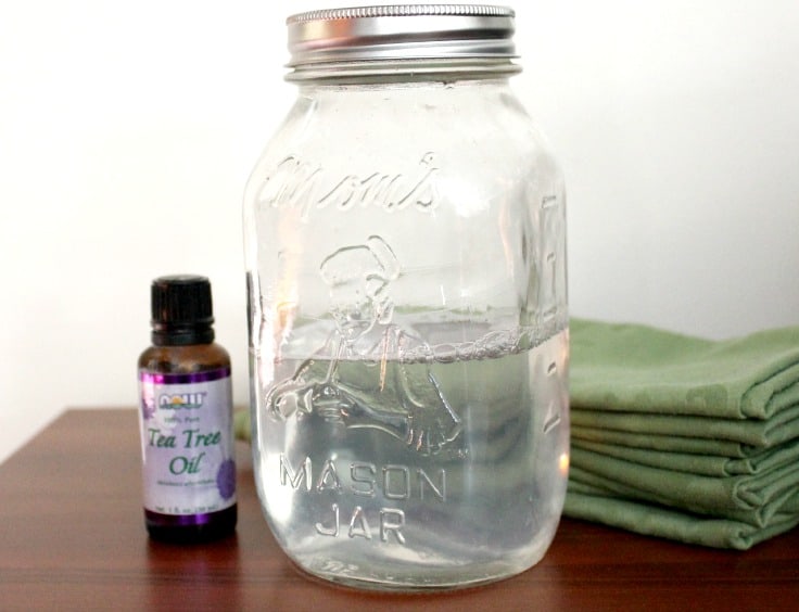 a jar of vinegar with a bottle of essential oils next to it