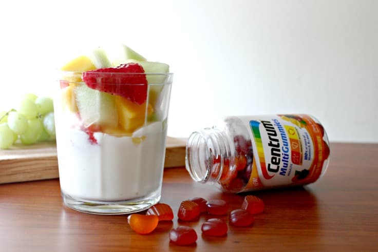 a bowl of yogurt with fruit near a bottle of vitamins