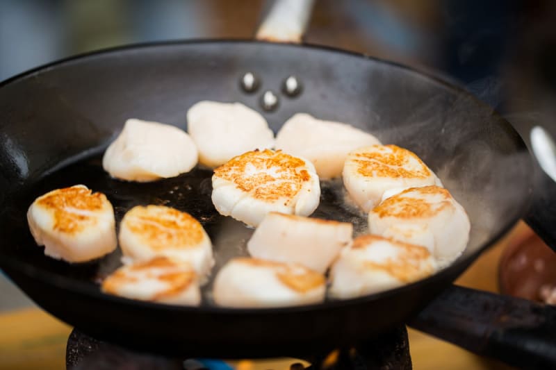 scallops frying in a black pan
