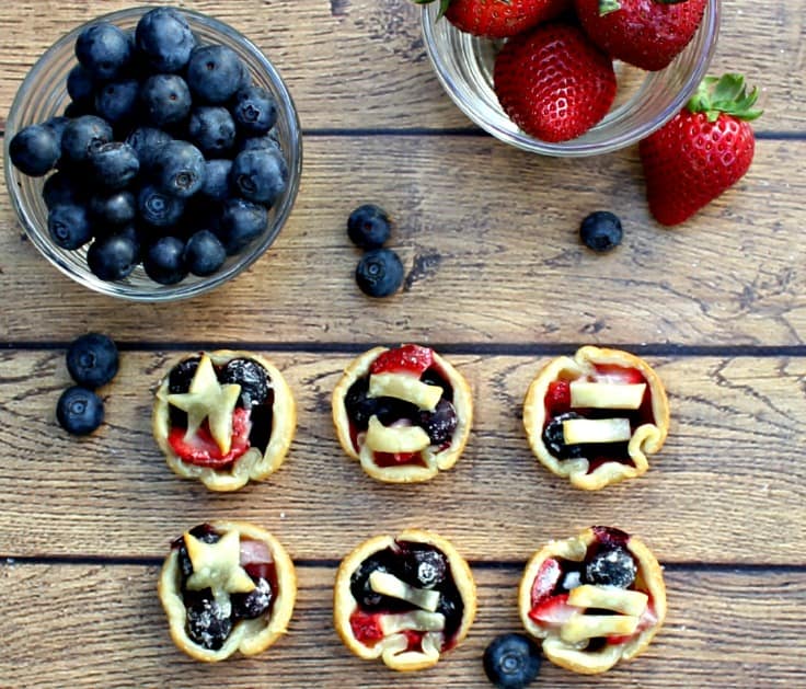 bowls of berries next to bite sized berry tarts
