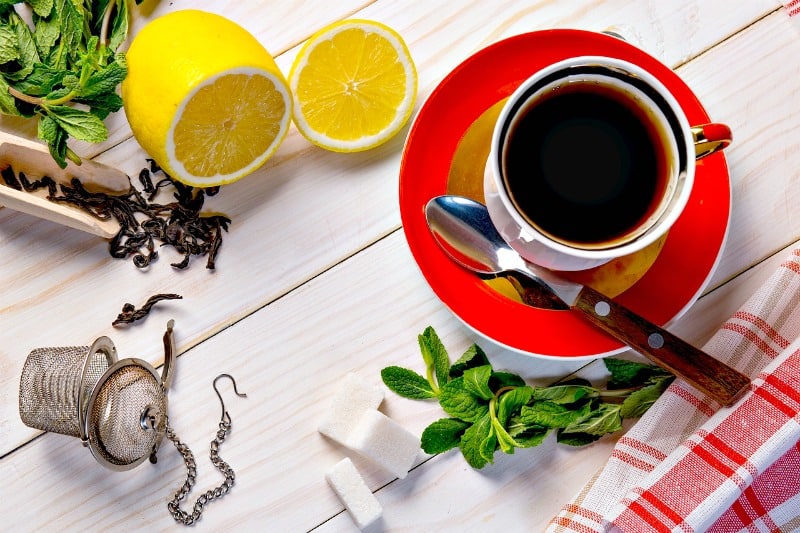 a cup of tea with lemon and mint leaves