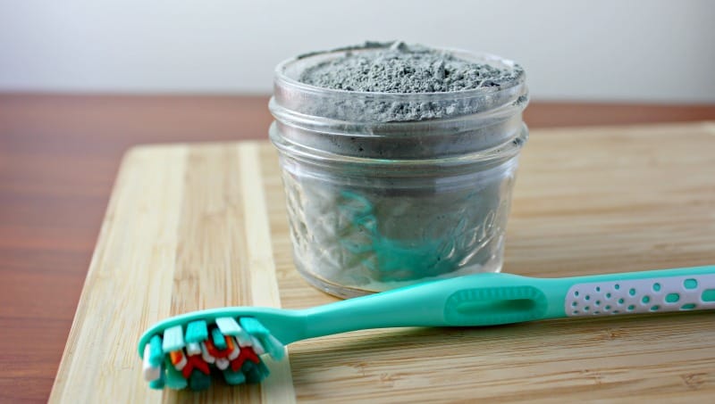 charcoal toothpaste in a jar with a toothbrush on the table