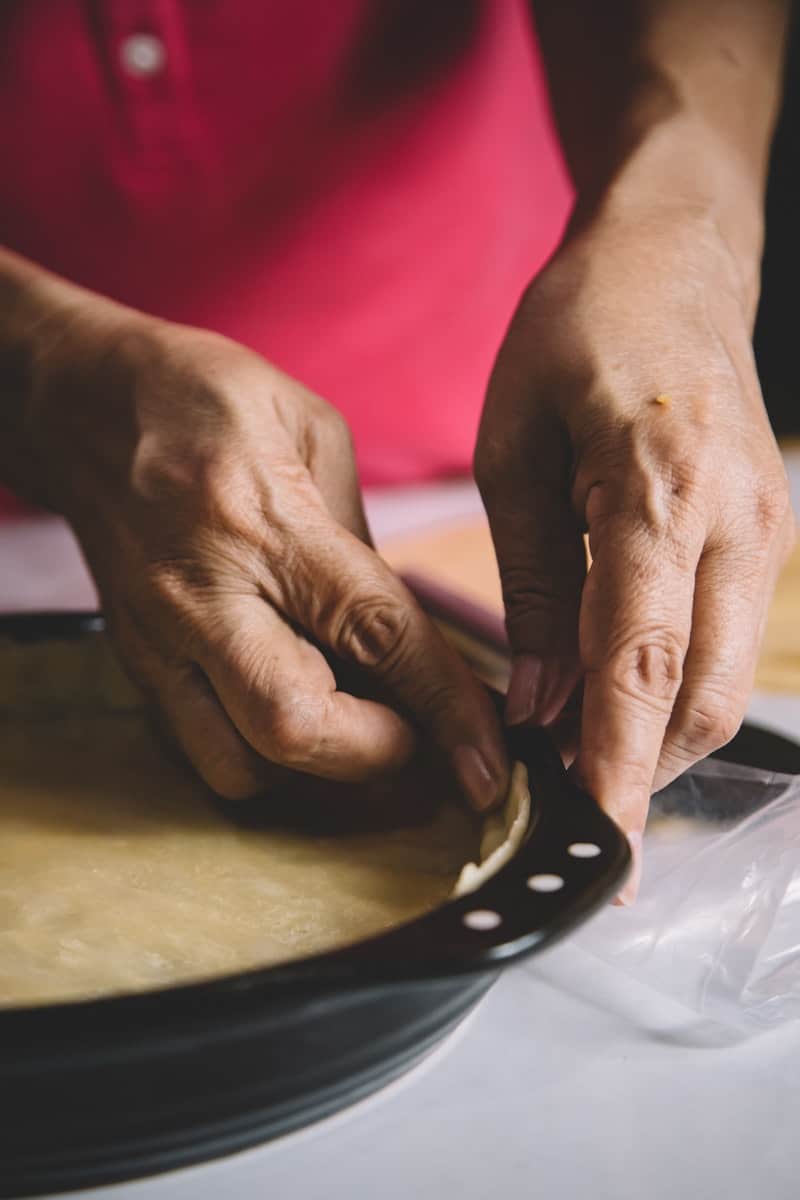 a woman making pie crust for a clean quiche recipe