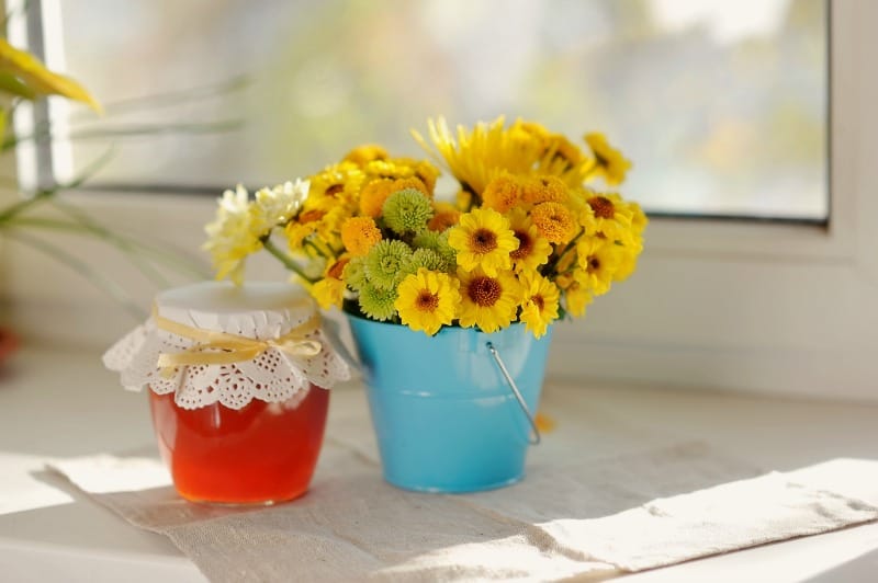 a pot of flowers and jar of jelly