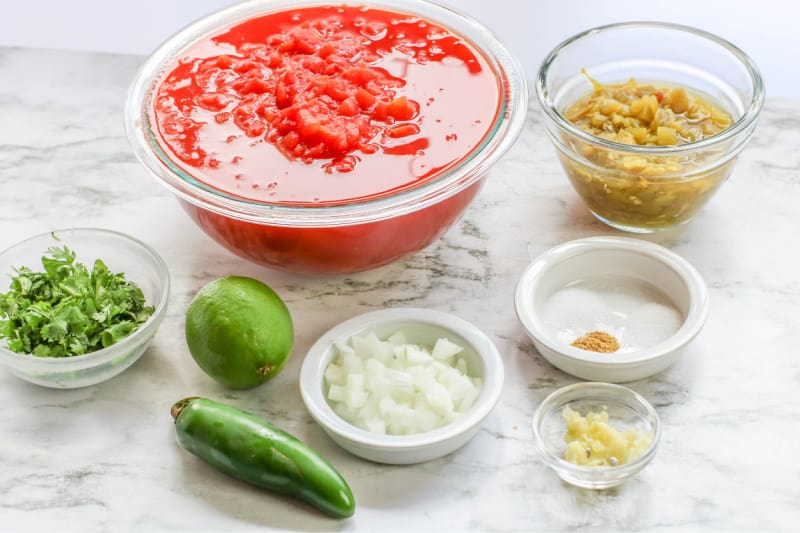 clear bowls on a counter with ingredients to make salsa