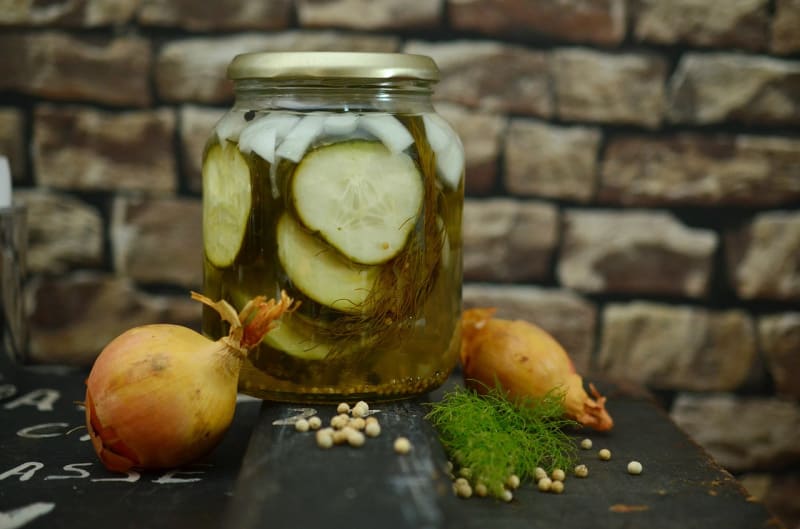 a jar of sandwich pickles near onions on the counter