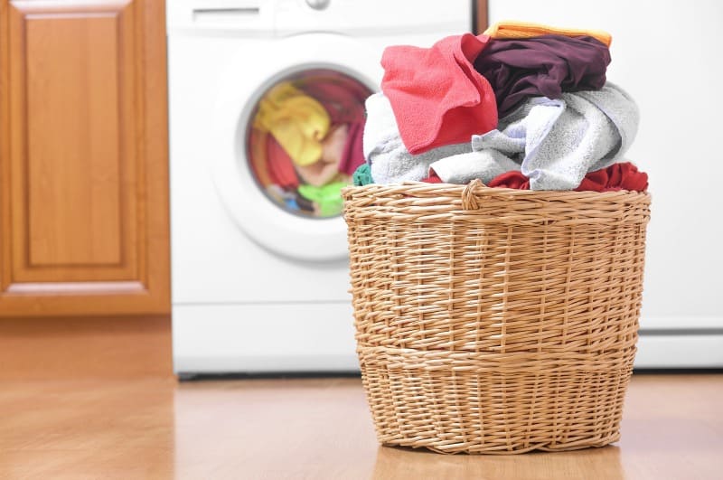 a basket of laundry in front of the washer and dryer