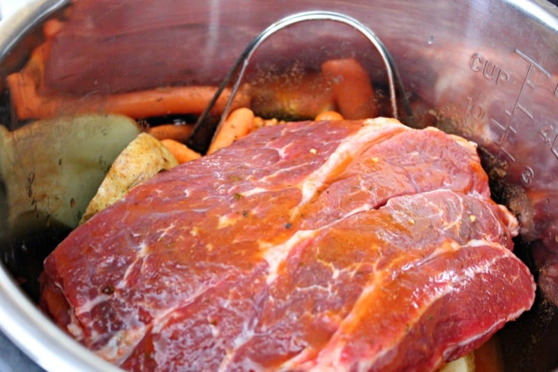 a chuck roast in a pressure cooker with vegetables