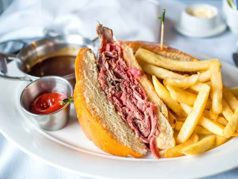 a shredded beef sandwich with French fries on a white plate