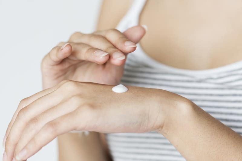 a woman putting cream on her hand