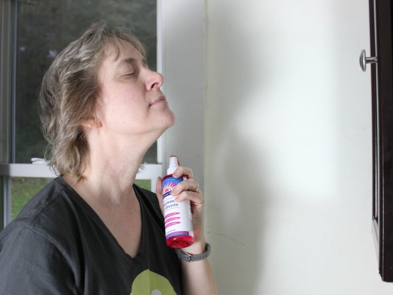 A woman spraying on rosewater